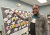 Giving Guide 2023: Literacy Pittsburgh A black man pinning a paper graduation hat onto a cork board with several others.