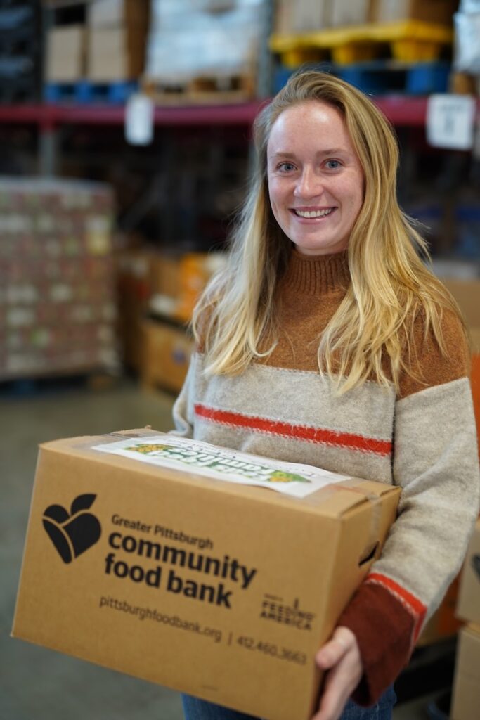 A woman carries a cardboard box from the Greater Pittsburgh Community Food Bank.