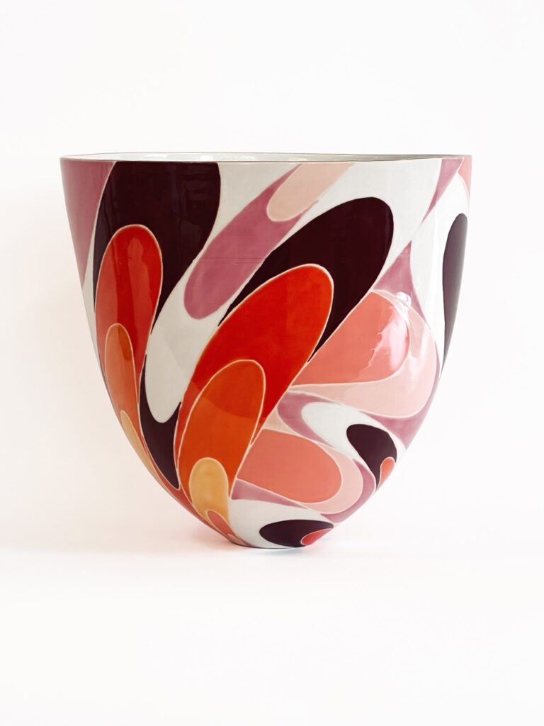 A tall oval bowl with red, orange, yellow, purple, white, and black blob-looking streaks as the pattern.