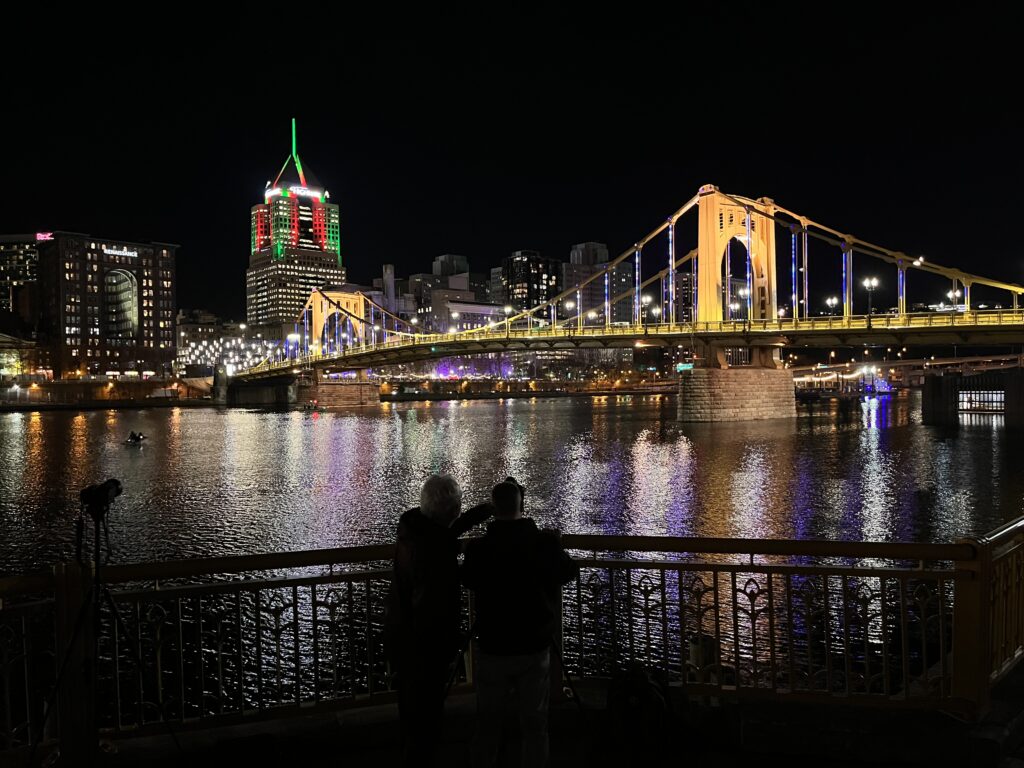 A night view of a river, bridge and illuminated city.