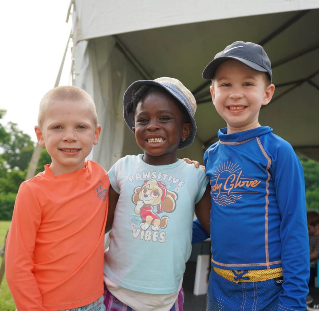 Three kids stand outside at a summer camp put on by JCC of Greater Pittsburgh.