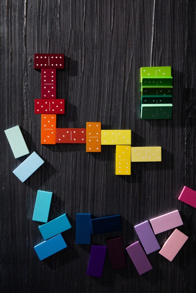 A variety of colored blocks in rainbow colors sit on a black background randomly.