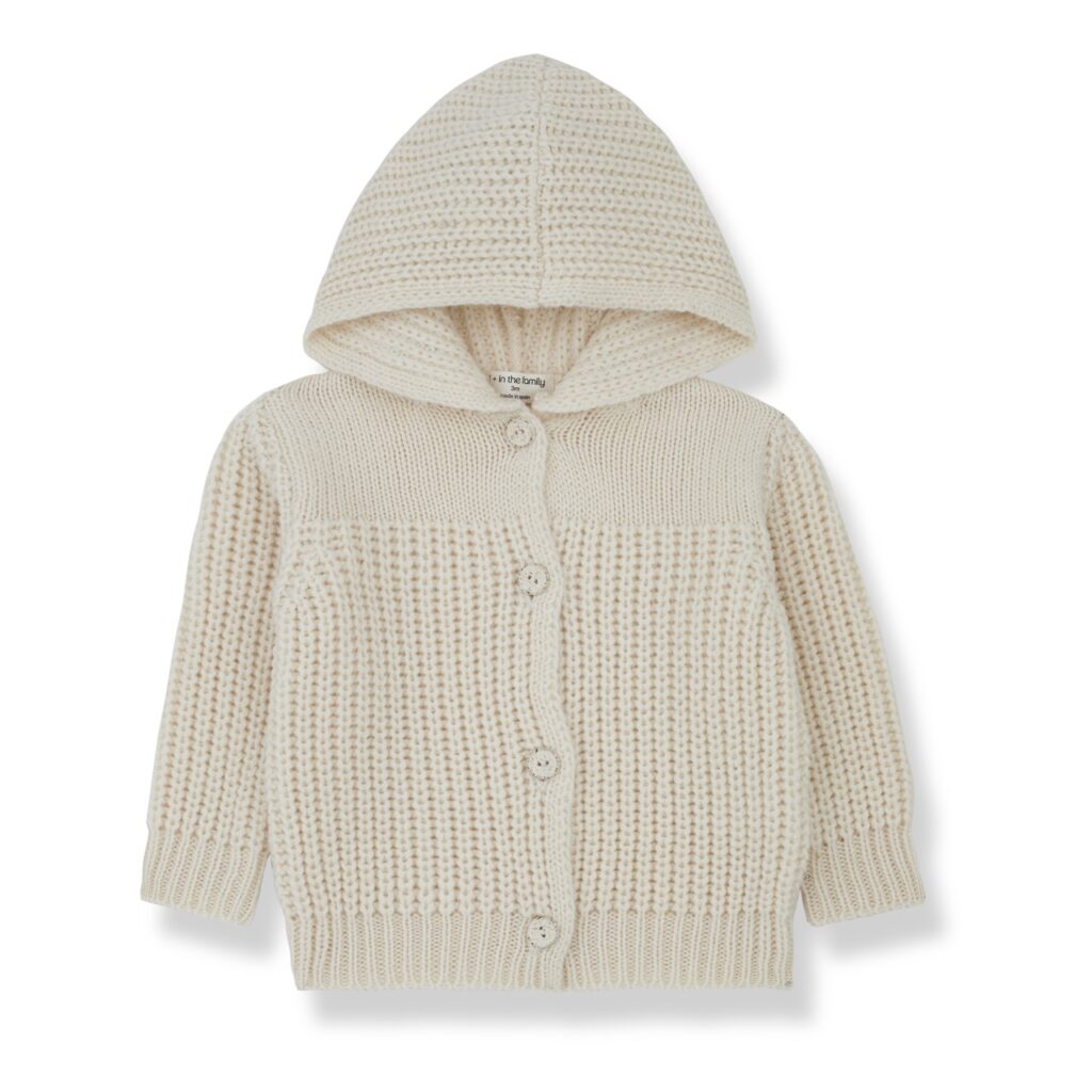 A kids knit white sweater jacket with a hood sits on a white background.