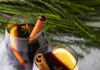 Clarence’s Mulled Wine Two stemless wine glasses with mulled wine sitting on a snowy surface with pine greens, garnished with a cinnamon stick, star anise, and an orange slice.