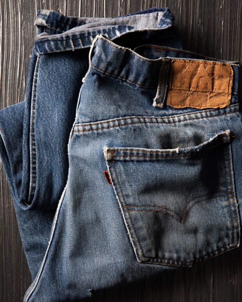 A pair of men's jeans sits folded up on a black table with the brown label sticking up.