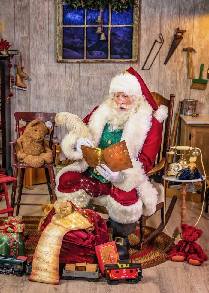 A Pittsburgh Santa Claus sits in a rocking chair with a book in his hand.