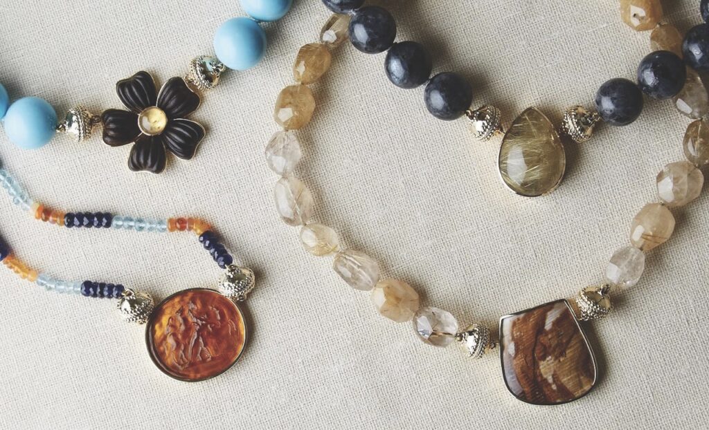 4 various stone necklaces with big centerpieces sit on a white background.