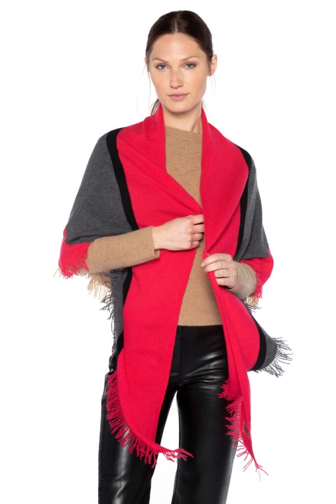 A woman wraps a black and red wrap around herself in from of a white background.