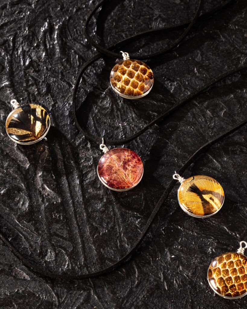 Various red and gold pendent necklaces on a black string sit on a black textured background.