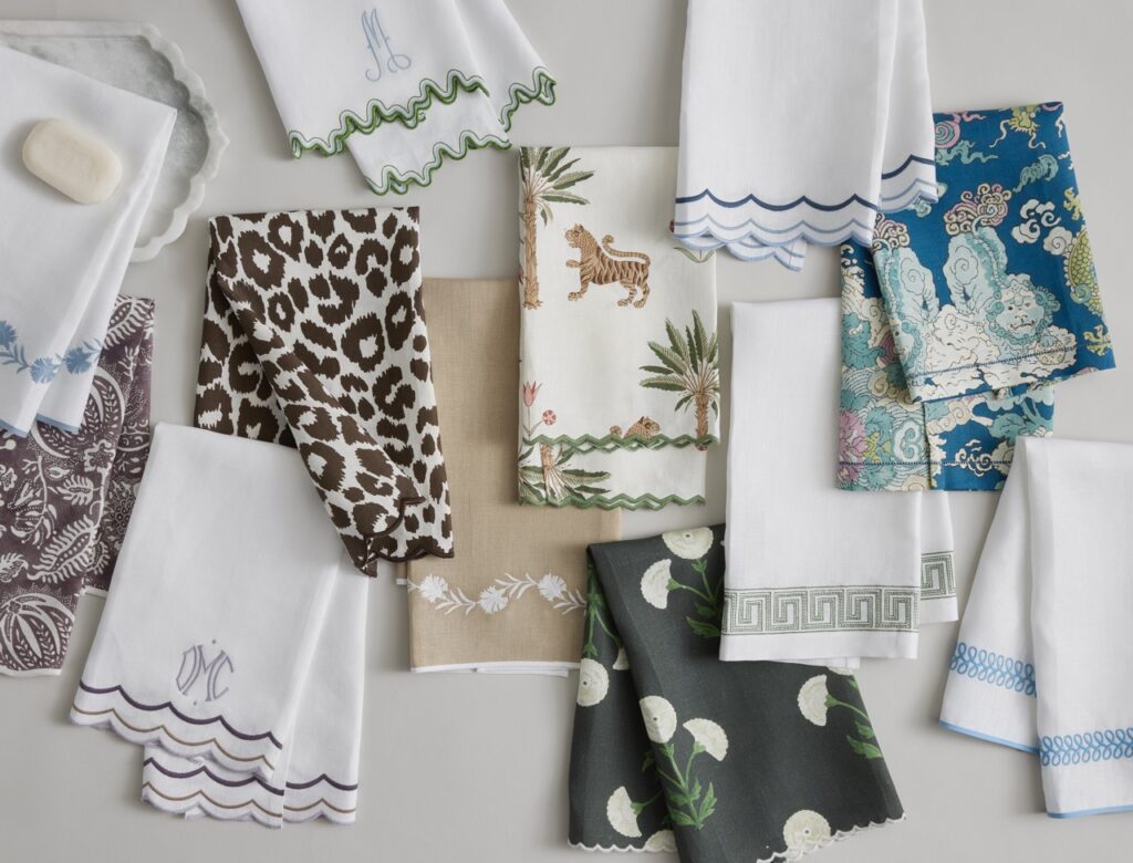 Various kitchen towels in animal patterns, white, and floral patterns sit folded in half on a white background.