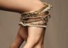 Holiday Giveaway 2023 A women's hand adorned with gold rings and bracelets