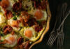 10 Recipes for a Magical Christmas Brunch An easy breakfast bake made with eggs, presented in a pie dish in the upper left corner, with a piece on a plate, and forks to the right of the pie dish.