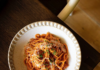 Pittsburgh Italian Restaurants with Homemade Pasta A white dish of spaghetti with red sauce on a brown table in Fish nor Fowl, Pittsburgh Italian restaurant.