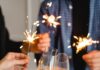 Toast to 2026 with These New Year’s Eve Parties in Pittsburgh Four people cheers champagne glasses with little sparklers lit in hand.