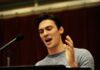 “The Perfect Mate” Musical Premieres in Pittsburgh A man stands behind a music stand and sings into a microphone in a grey shirt.