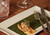 2 Pittsburgh Restaurants Make 2024 James Beard Awards Semi-Finalists List A dark round plate displays flatbread crisps with like herb toppings at Pusadee's Garden in Pittsburgh, a James Beard Awards Semi-Finalist