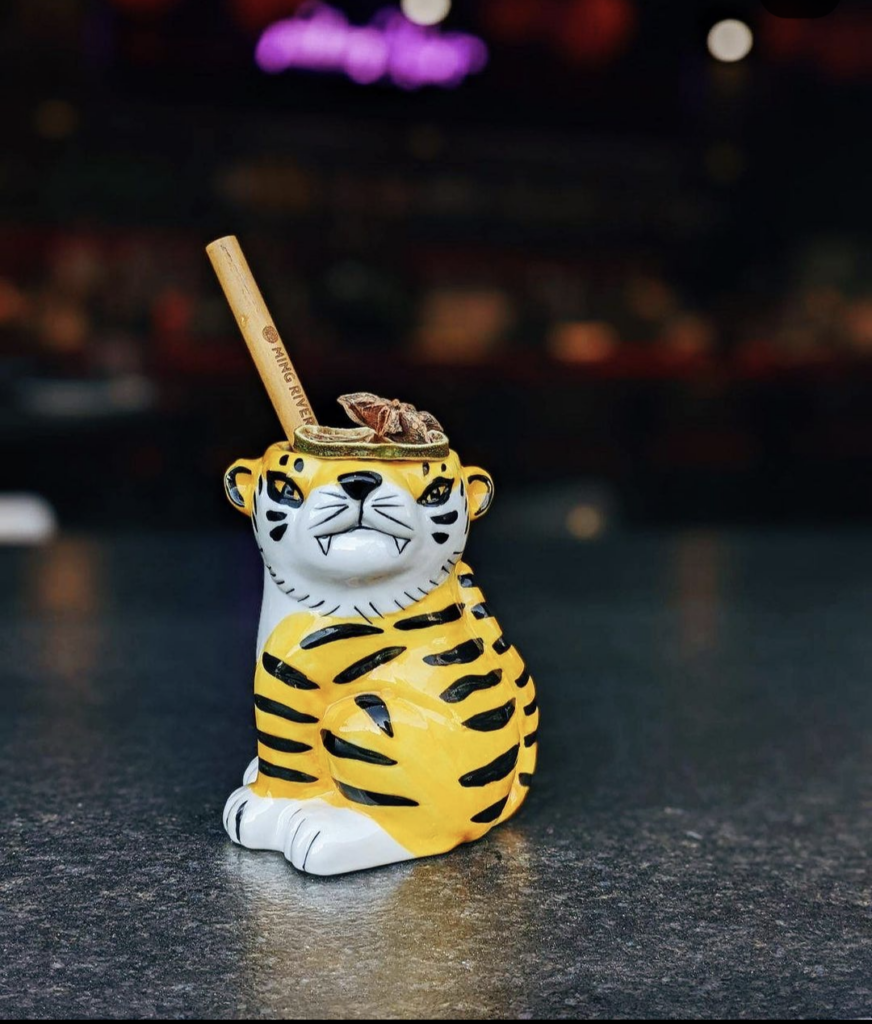 A glass in the shape and colors of a tiger with a piece of wood sticking out of it and anise star on top, sitting on a counter at Parlor Dim Sum in Pittsburgh