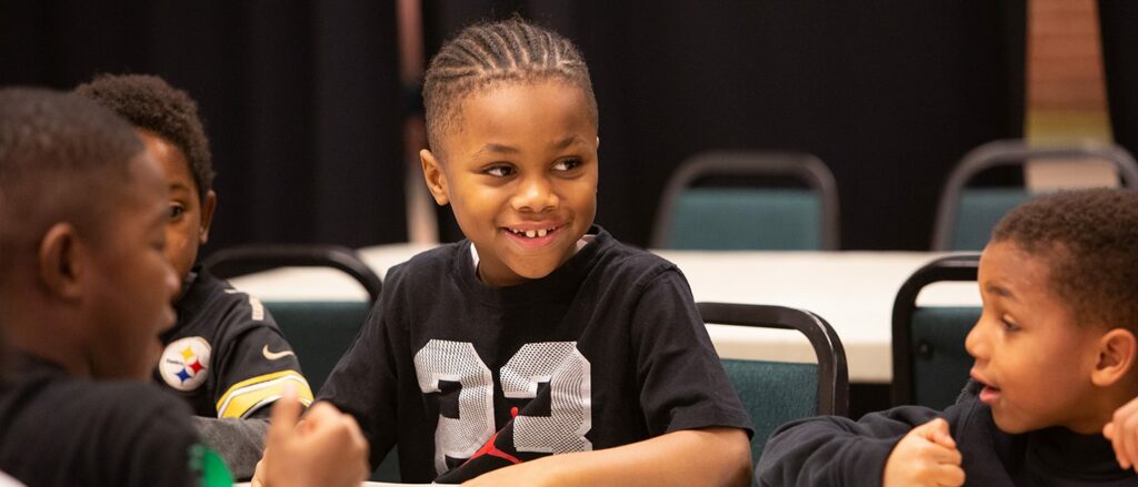 A boy in a Steelers jersey sits at a table with other little boys also in Steelers merchandise in Pittsburgh.