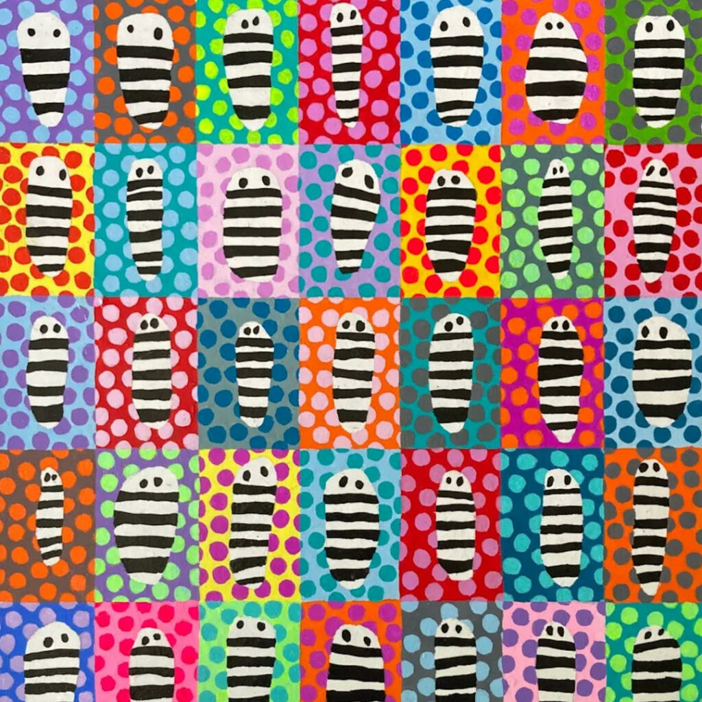 A piece of art features different colored pods with polka dots and little black and white striped creatures within.