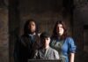Last Minute Tickets in Pittsburgh: February 22-27 A man in dark clothes and a woman in a blue long dress stand behind her son who is in a cap and holding a window pane.