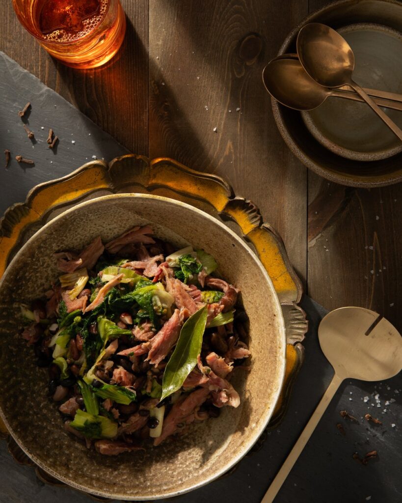 An aerial view of a light brown bowl filled with Ham, Beans, and Greens
