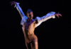March Calendar at New Hazlett Theater A male ballet dancer in nude tights and an open white button up short leaps into the air with his arms up against a black background.