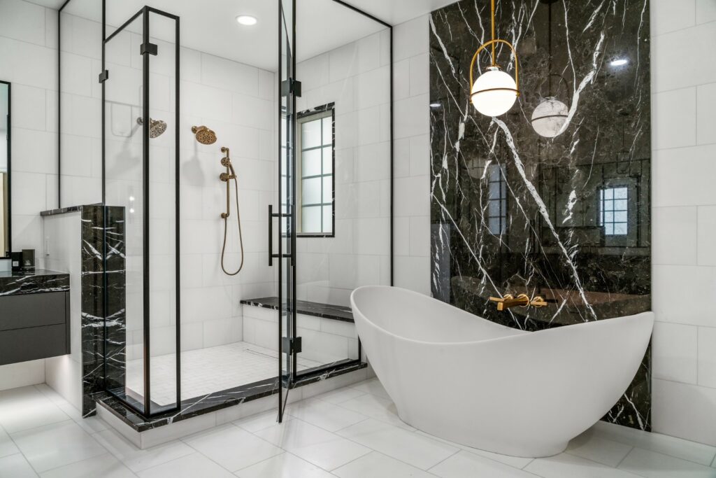 A white oval tub surrounded by black an white marble stone