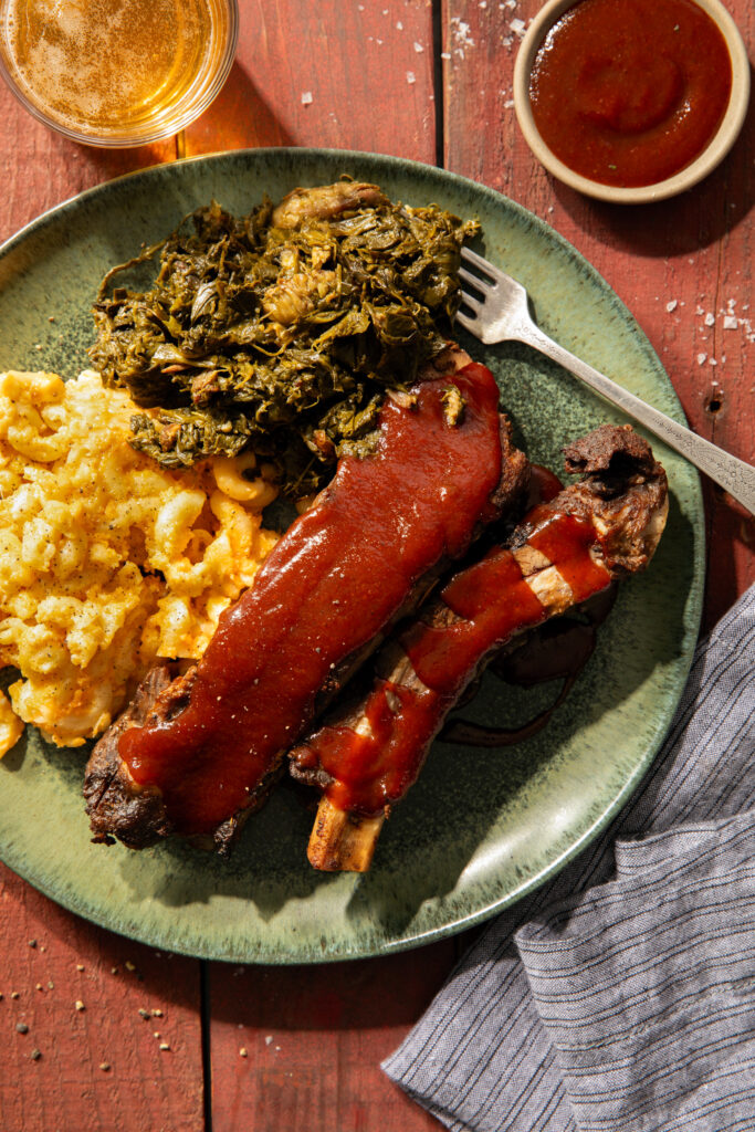 A green plate holds a rack of ribs, collard greens, and mac and cheese from Cuddy's.