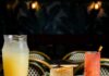 Cinco de Mayo Specials at Pittsburgh Restaurants Three drink glasses in yellow and orange and red sit amongst a table of tacos on various plates with a menu sitting in the bottom left corner for a Pittsburgh Cinco de Mayo celebration.