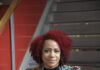August Wilson African American Cultural Center Debuts its ’23-’24 Season Nicole Hannah-Jones, a speaker in AWAACC's TRUTHSayers series sits on a set of stairs with a colorful printed blazer and red, curly hair.