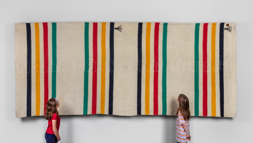 Two little girls look up at Marie Watt's Quilts of Steel exhibit at the Carnegie Museum of Art.