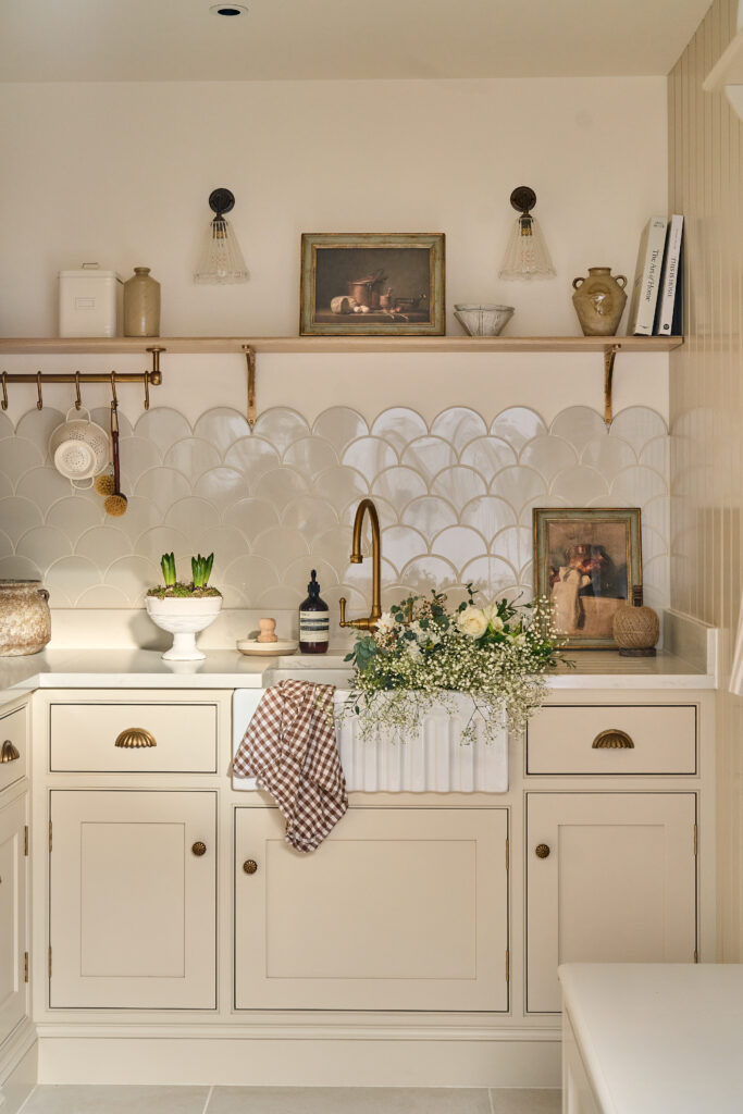 An ivory, creamy colored kitchen with brass/gold handles and a reflective backsplash from Allegheny Millwork & Lumber.