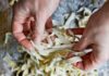 Italian Cooking Classes in Pittsburgh A person pulling handmade pasta on top of a marble table with a bowl of flour and a bowl of eggs at the bottom.