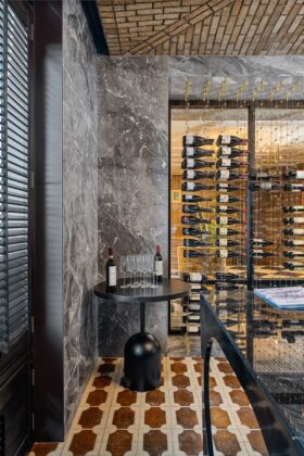 Marble wall with wine rack, marble floor and other stone features by Armina Stone at the Fawn & Fable restaurant and Nemacolin.