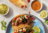 Best Latin Food in Pittsburgh A plate of latin tacos sit on a blue plate with additional dipping sauces from a restaurant in Pittsburgh.
