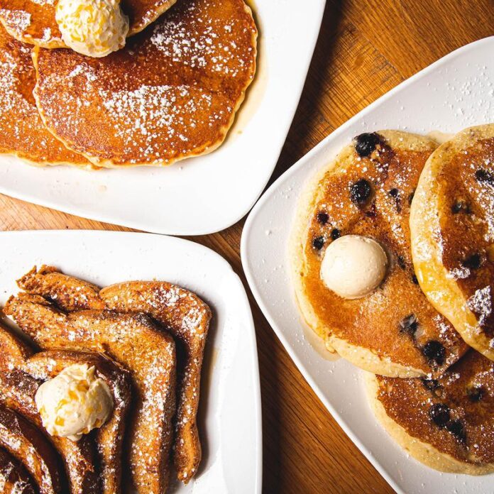 Two plates of pancakes and one of french toast sit in a triangle shape on a table at the breakfast stop Square Cafe in Pittsburgh.