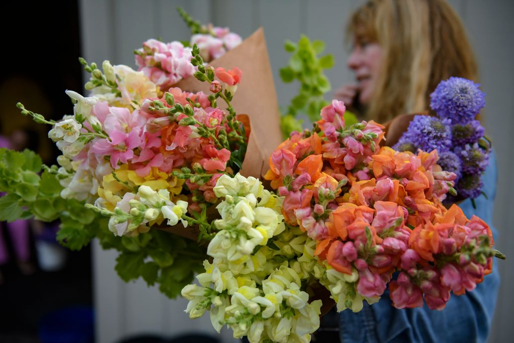 A woman at the Pittsburgh Greater Flower Collective carries a handfull of florals in orange, yellow, and pink.