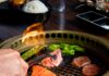 7 BBQ Pit Stops in Pittsburgh A person uses tongs to roast a piece of meat on a BBQ at Pittsburgh Restaurant COBRA.