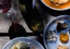 Plant-Based Eats in Pittsburgh Two plates of plant-based foods in Pittsburgh like potato pancakes and other small bites with a glass and bottle of wine about it.