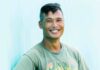 Chef Rafael Vencio Creates Pittsburgh Filipino Pop-Up, Amboy Rafael Vencio of Amboy in Pittsburgh stands against a blue background in a green graphic shirt with a smile on his face and a crate of fresh zucchini in his right arm.