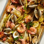 Roasted Shrimp, Clams, Asparagus and Leeks on a sheet pan, garnished with lemon wedges. Sheet Pan Roasted Shrimp, Clams, Asparagus and Leeks Recipe