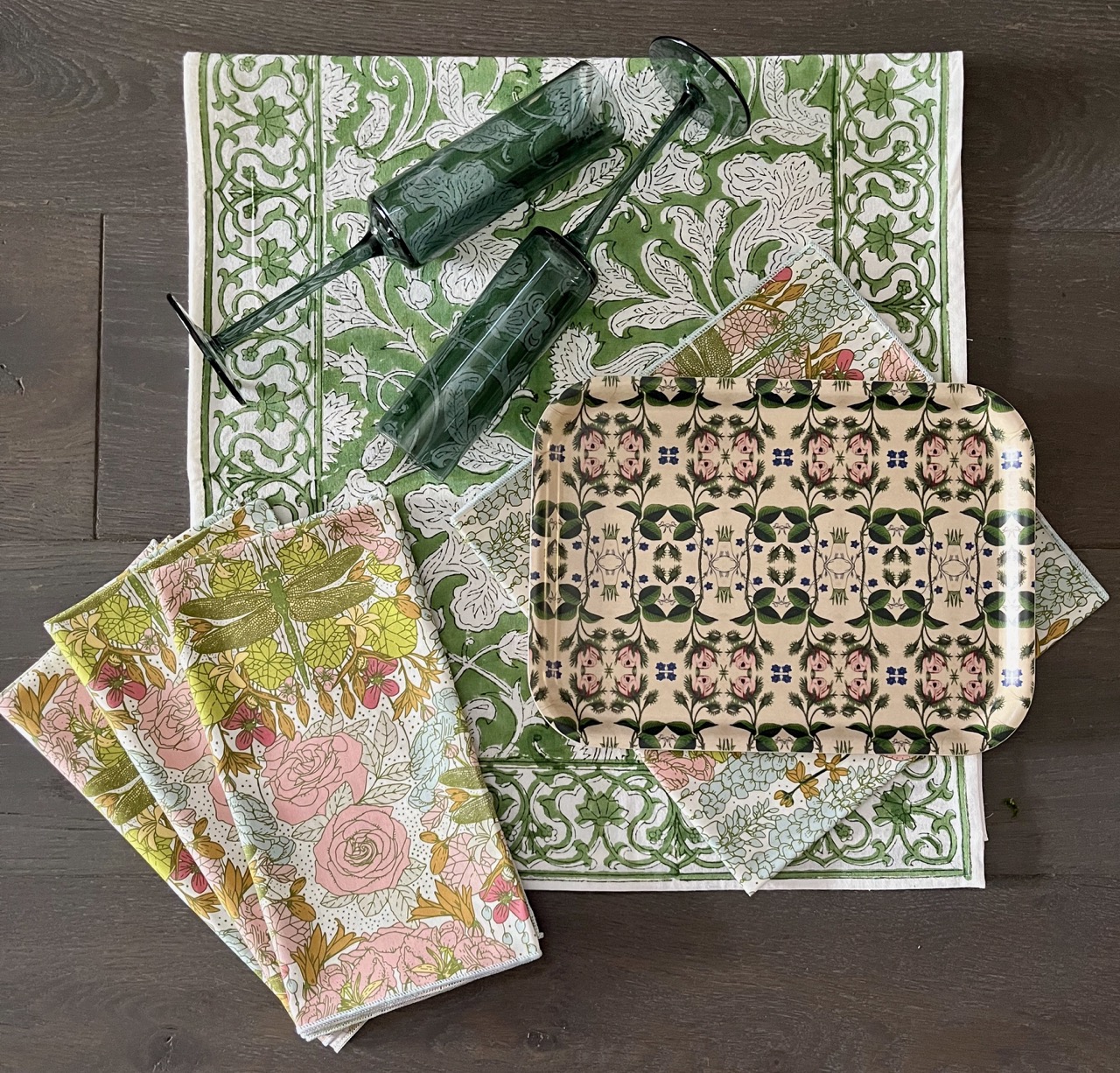 Printed tablecloths in pink and green sit below two green champagne flutes.