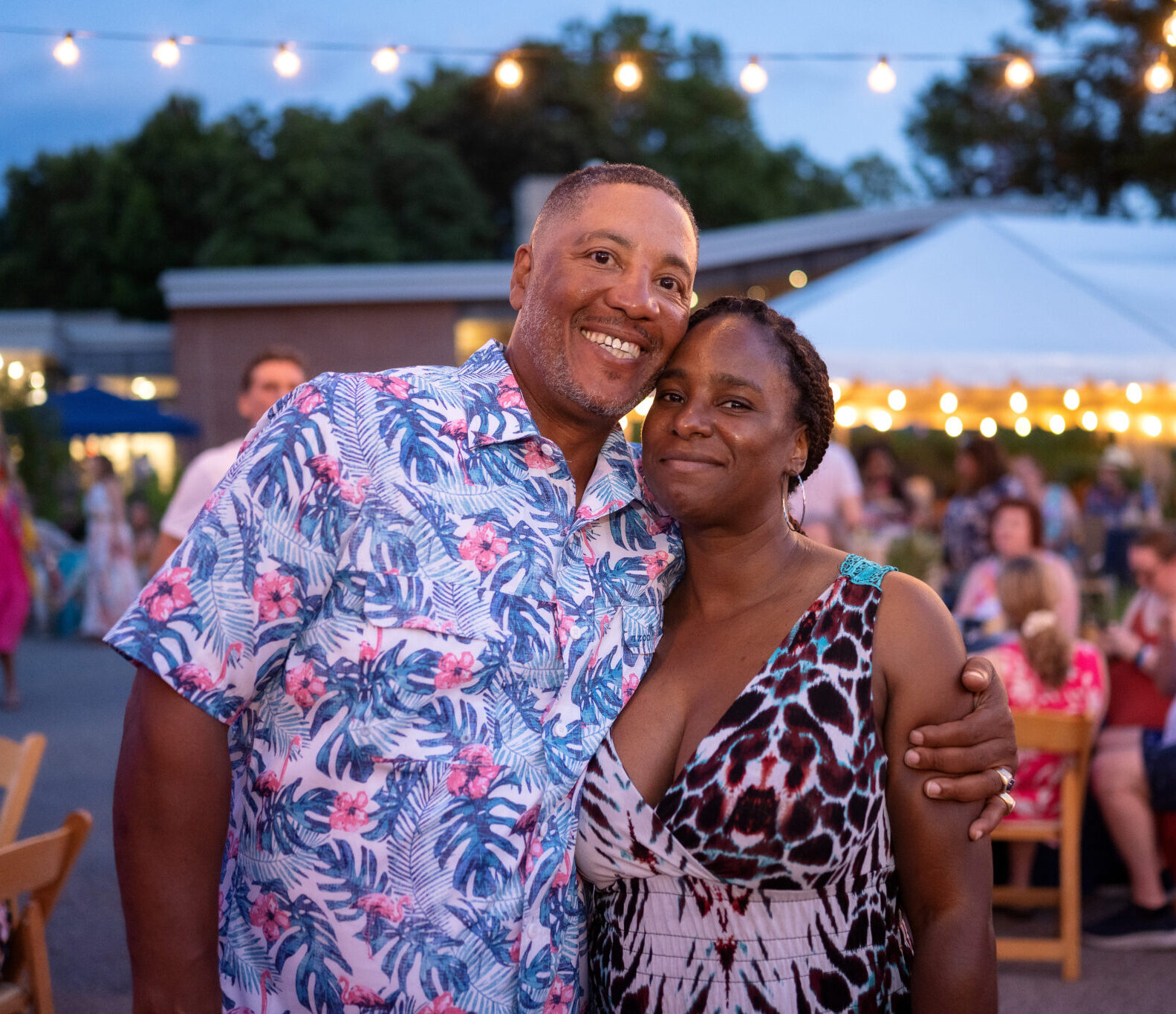 Two people pose together in tropical print clothes at a Night in the Tropics at the aviary.