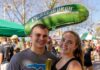 12 Must-Try Vendors at Picklesburgh 2025 A man and woman stand with a pickle and lemonade in hand as a green Picklesburgh balloon floats behind them.