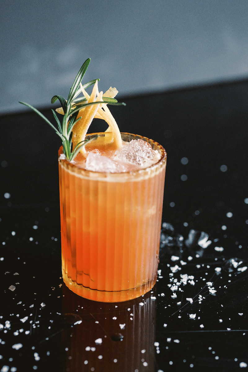 A pink cocktail on a black background with a sprinkle of salt