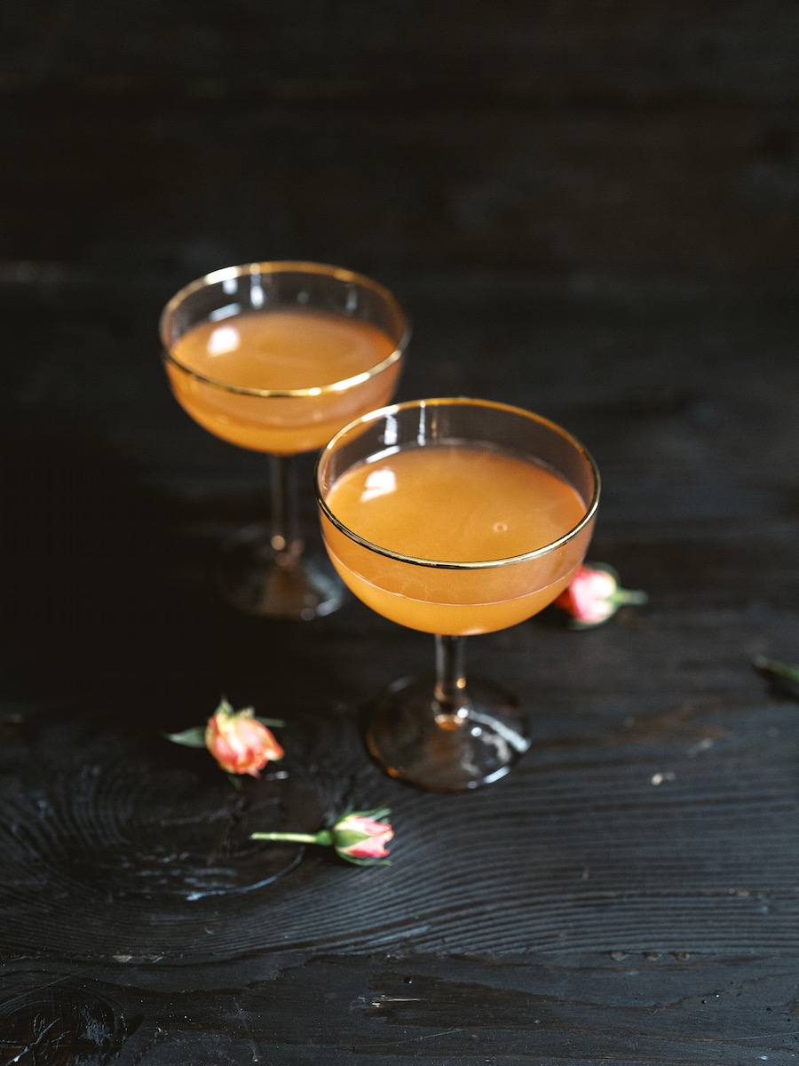 A pale orange cocktail on a black background 