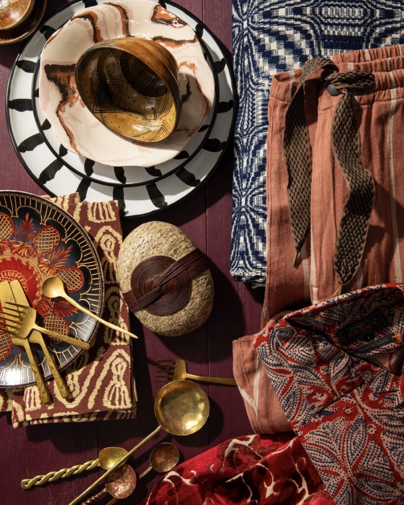 Ancient fashion and design materials such as fabrics and tableware sit against an auburn background.