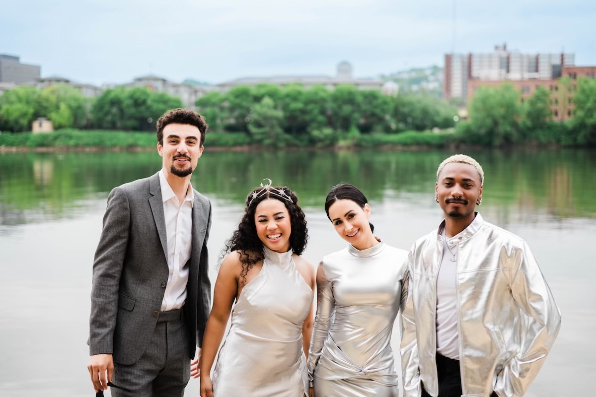 Four people dressed up in stylish clothing in front of a Pittsburgh riverfront for Riverlife's Party at the Pier:Galactic.