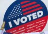 Pennsylvania Voter Guide A person holds an American flag and vote sticker after voting in PA.