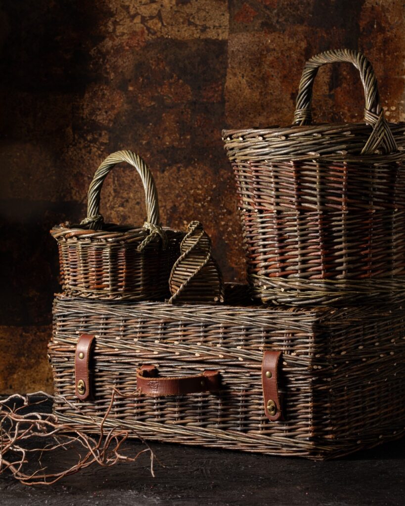 A series of Dan Brockett's handwoven baskets sit on top of each other against a brown background.